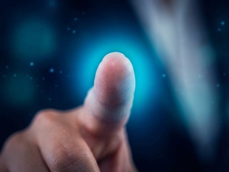 Finger reaching toward a glowing blue point of light in a dark speckled space